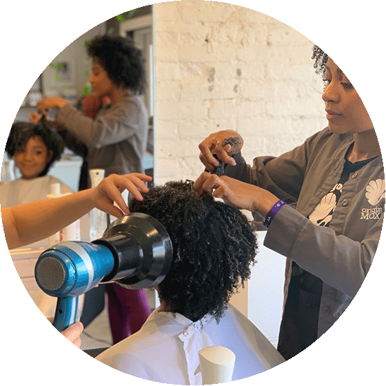 Hairstylists at the Original Moxie Salon doing a client's hair