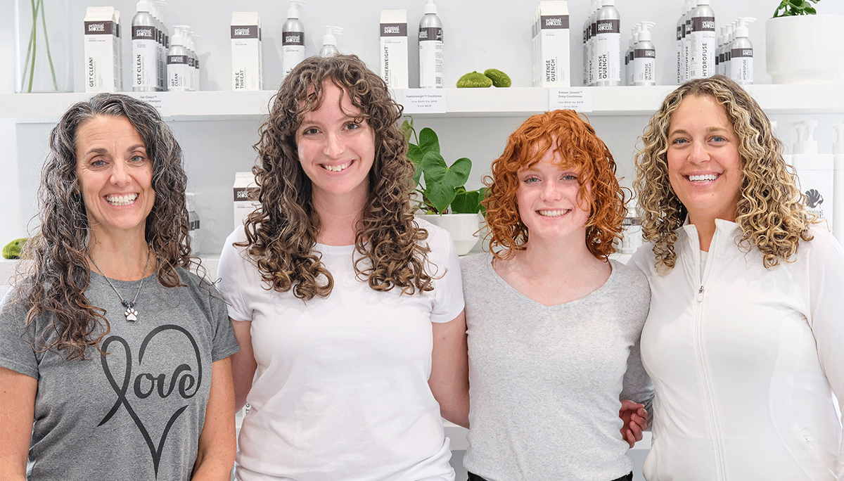 A group of women with curly hair smiling