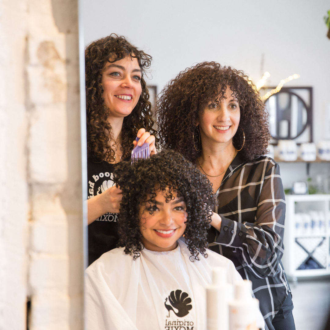 Original Moxie staff members touching a client's hair while smiling