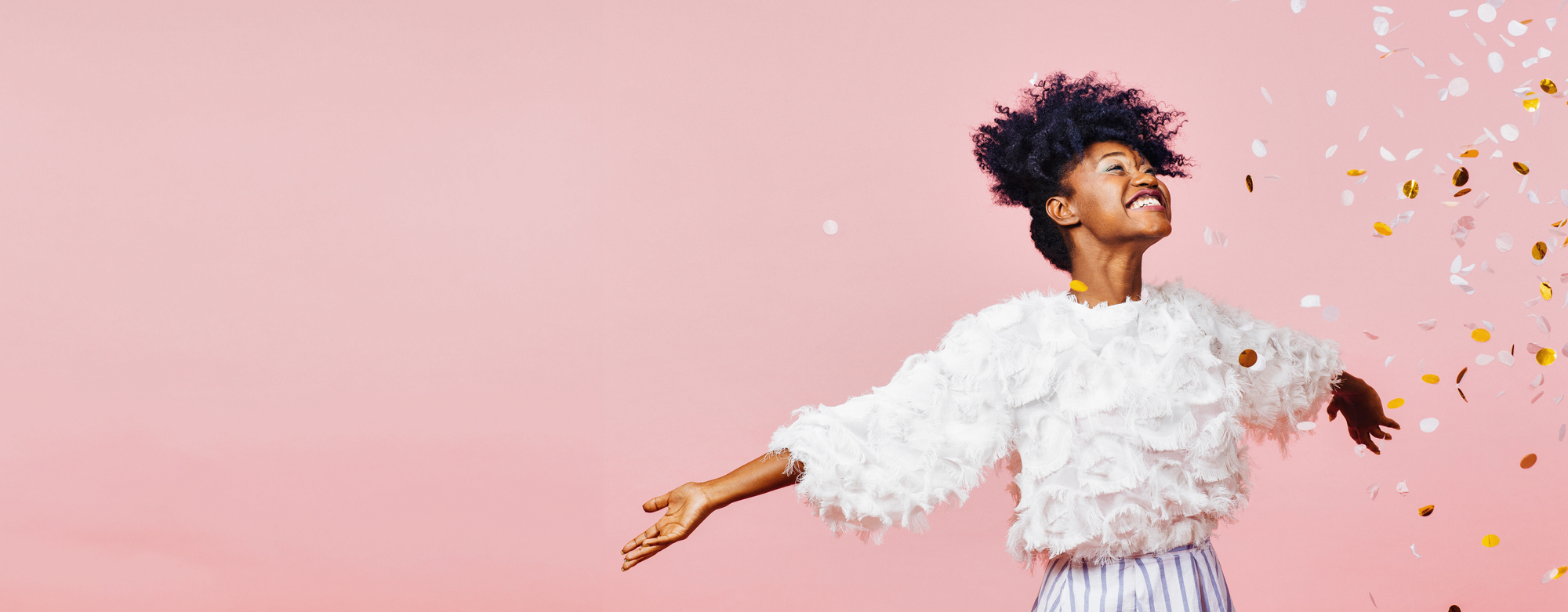 Young woman with curly hair throwing confetti