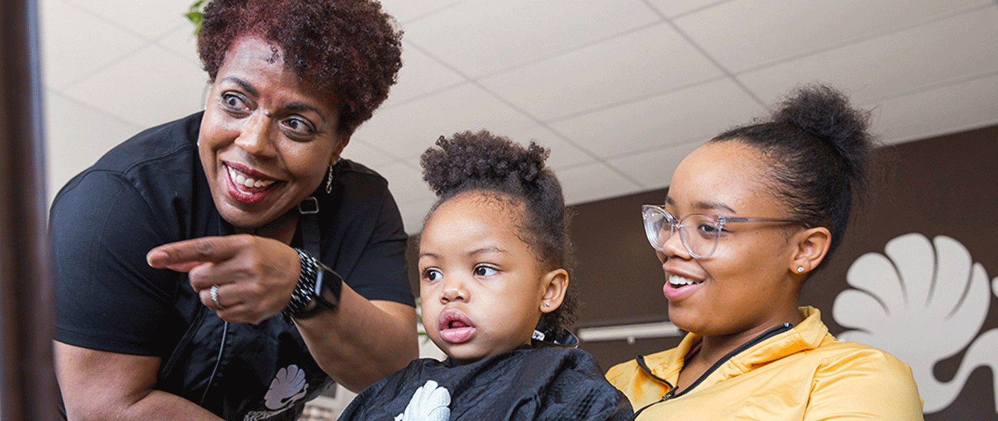 A child and their mother receiving curl coaching from a hairstylist